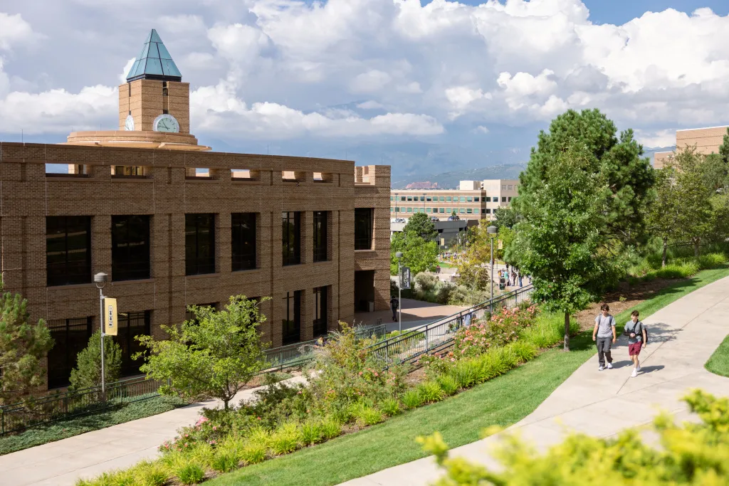 Students walking together on campus with El Pomar clock tower in the background